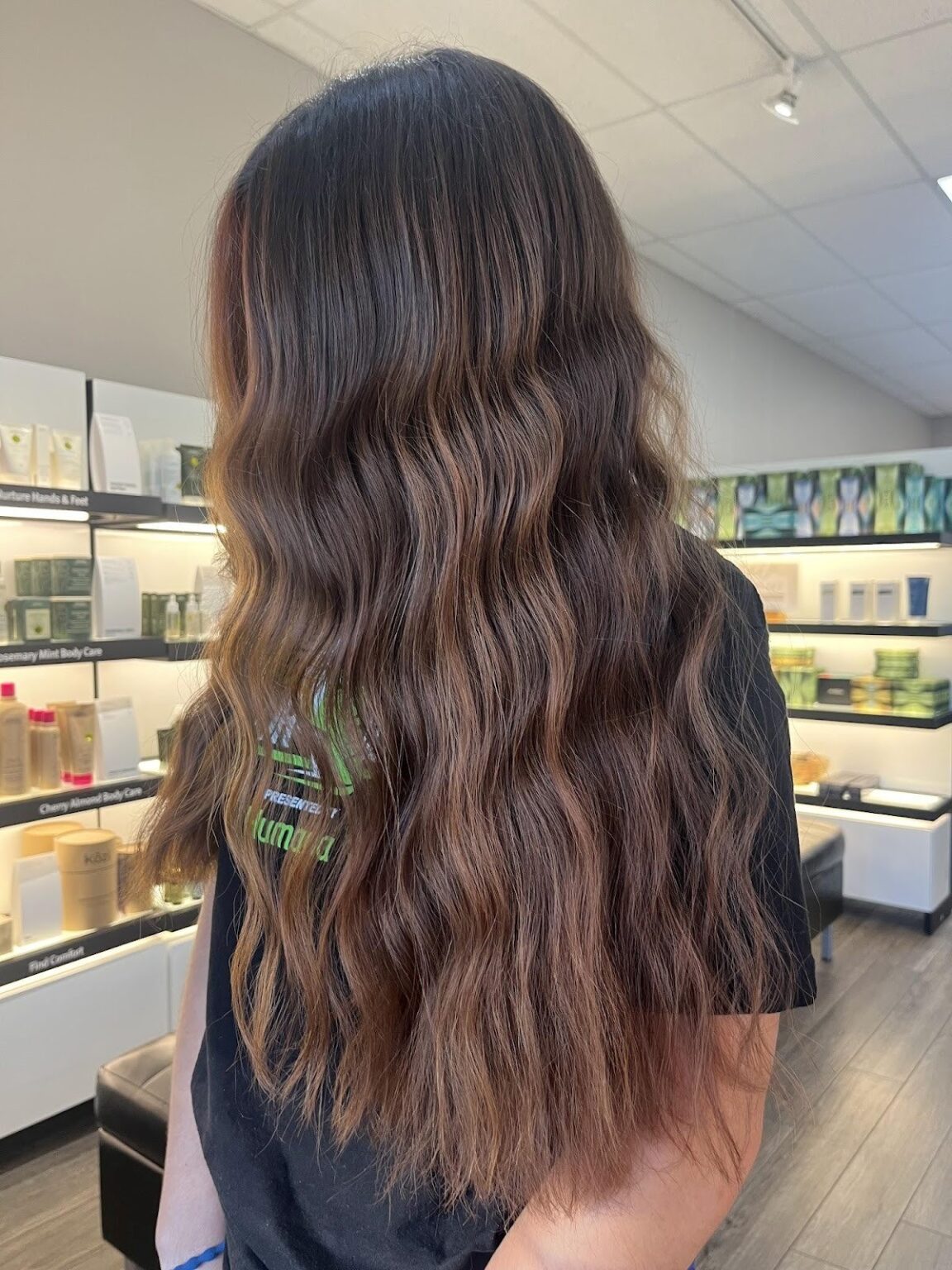 Side view of long wavy hair with copper cashmere tones, featuring soft warm dimension and natural blended color in a salon setting. - Pure Salon Spa, KY